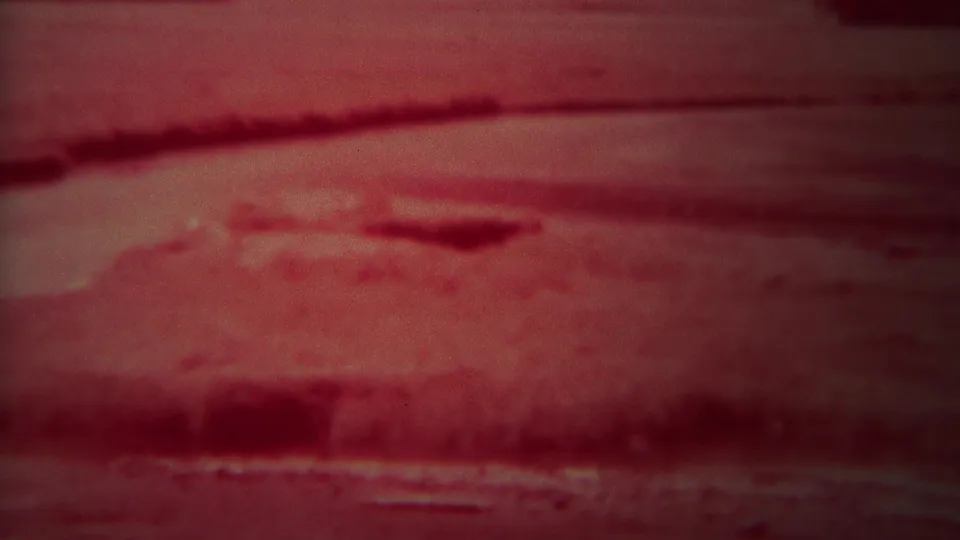 1967 Yellowstone 8mm frame showing a dark red river view with a blurred shoreline and horizontal bands of moving water.