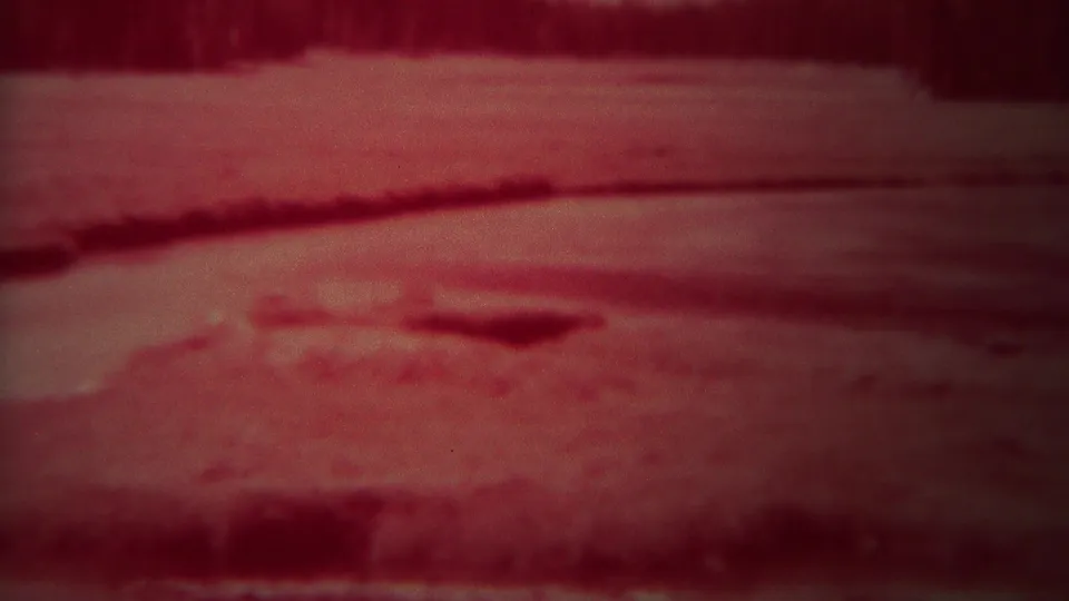 1967 Yellowstone 8mm frame of a red-tinted night river surface with faint ripples and an indistinct background bank.