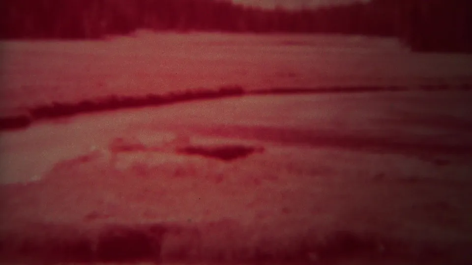 1967 Yellowstone frame with red color shift, pale snow or ice in the foreground, and a dark forest band in the distance.