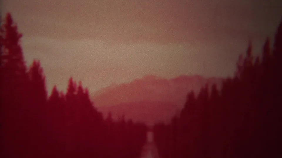 The final frame shows a pine-lined Yellowstone view with distant mountains and pronounced red film fading.