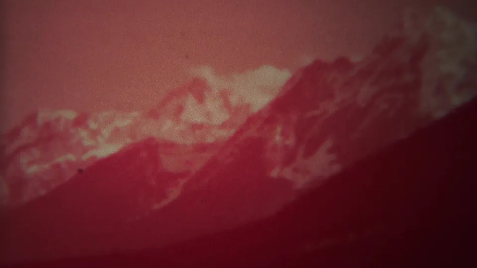 1967 Yellowstone-area frame showing a red-faded mountain range with dark foreground slopes and pale peak highlights.