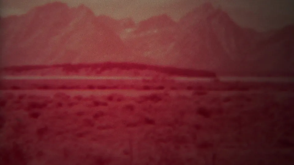 A 1967 8mm frame shows the same red-tinted Wyoming plain with low vegetation and softened mountain shapes.