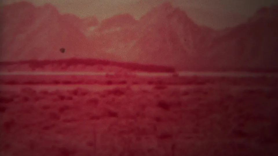 The closing frame shows the Yellowstone-area landscape with red color shift, distant mountains, and a small dark film mark.