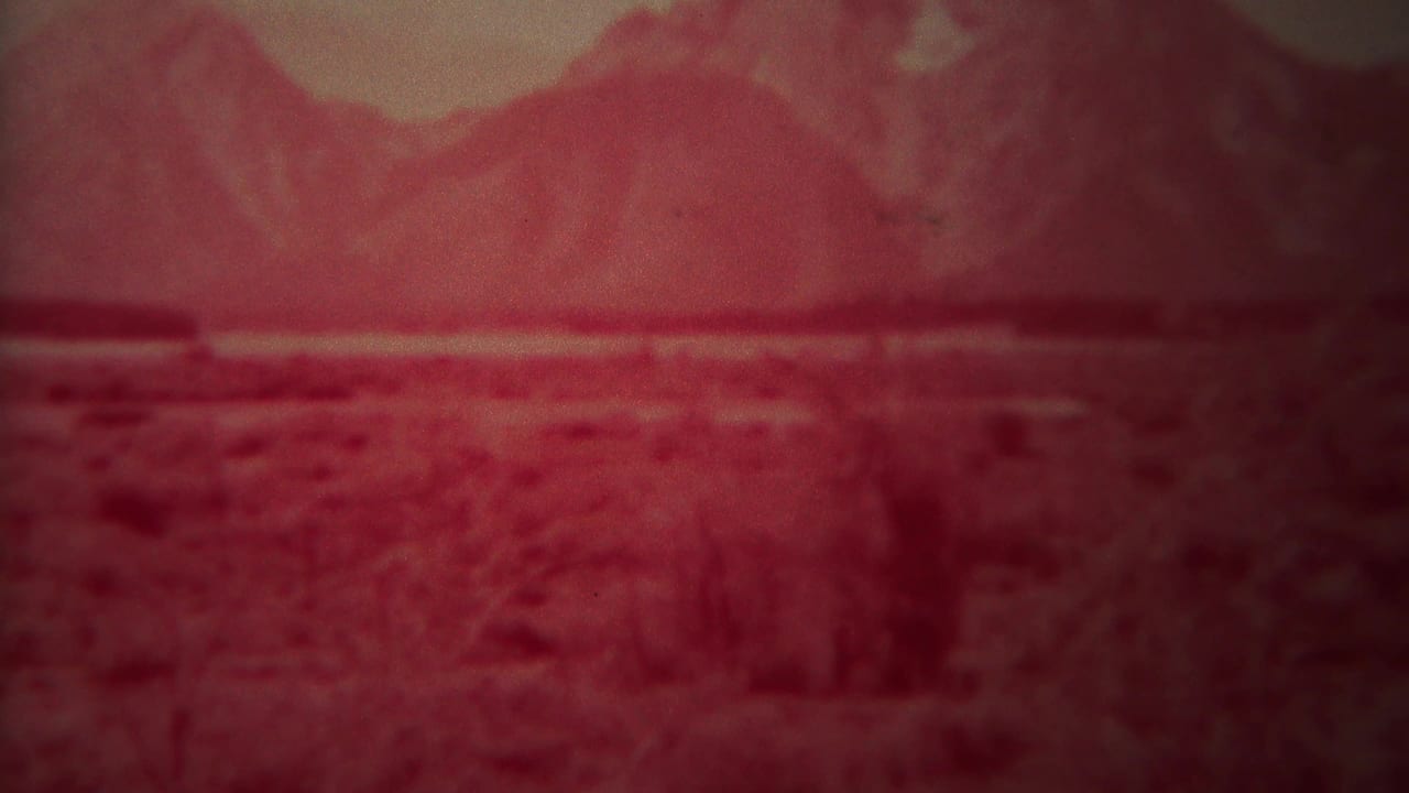 Red-tinted view of an open plain with distant mountains and low brush.
