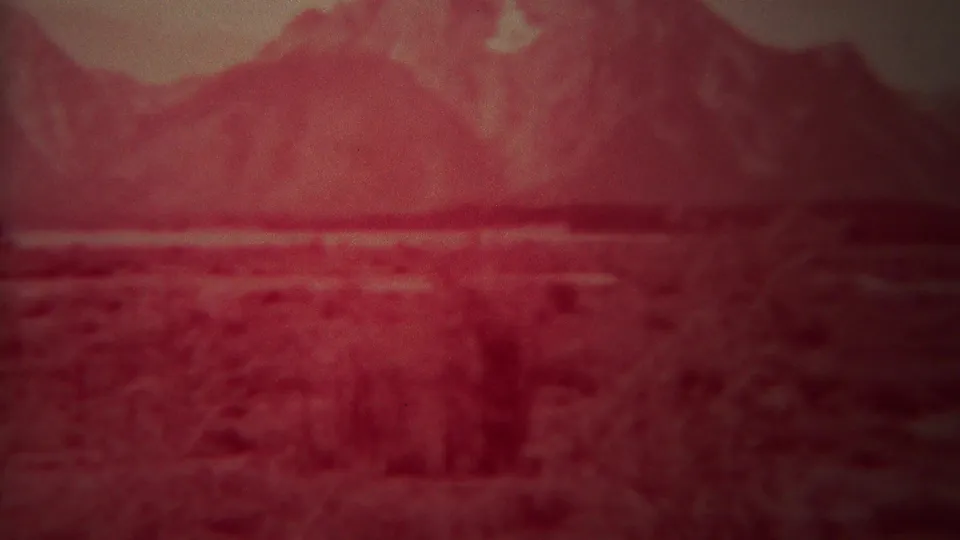 Red-faded 8mm travel footage of the Yellowstone, Wyoming area, with a broad plain leading toward hazy mountains.