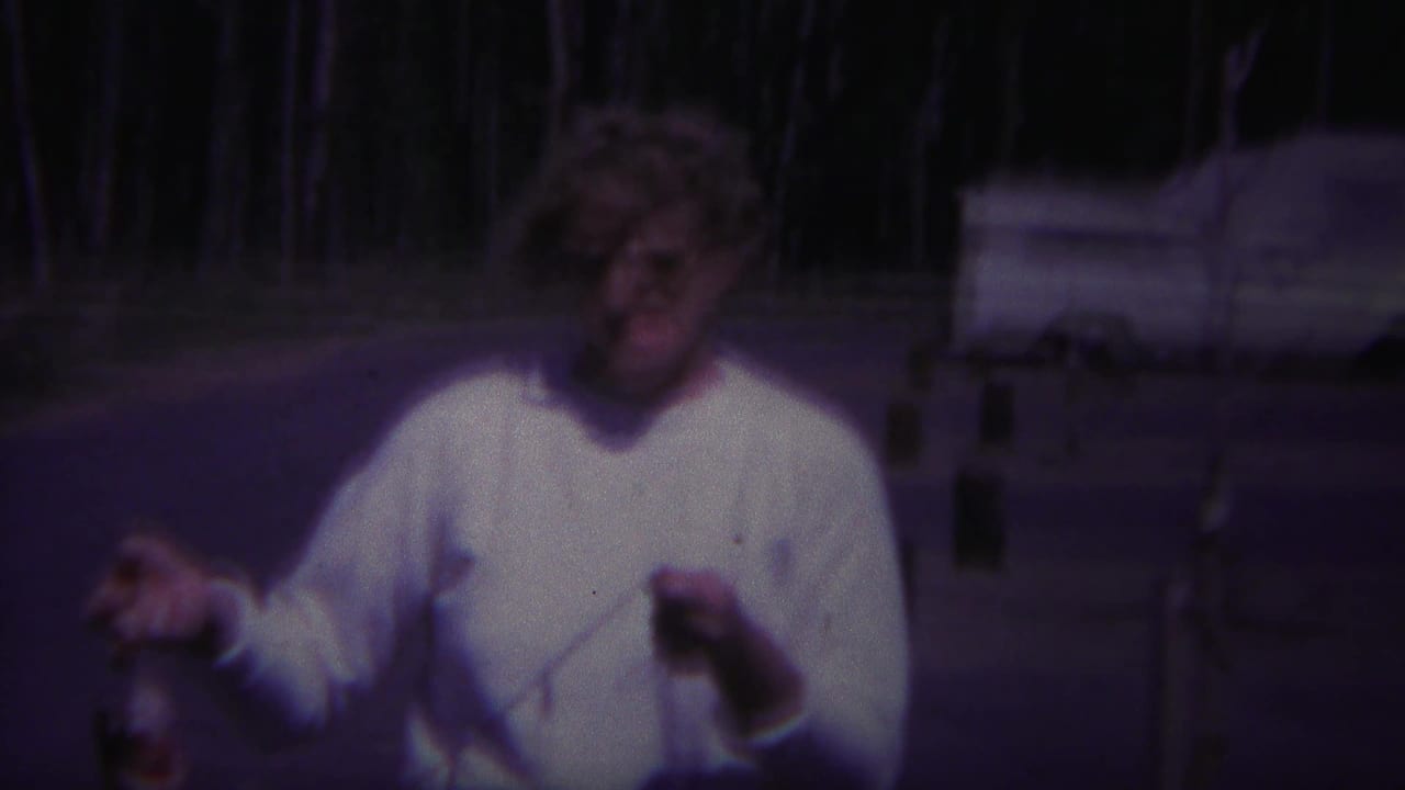 Woman in a white sweater holding up a fish stringer near a campground road.