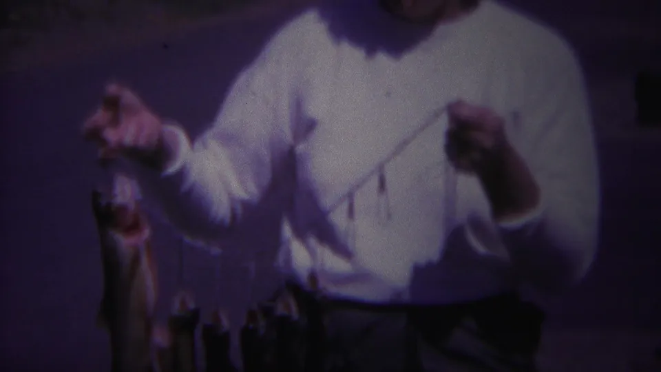 A closer, purple-shifted 8mm frame shows the woman displaying several caught fish on a stringer at the campground.