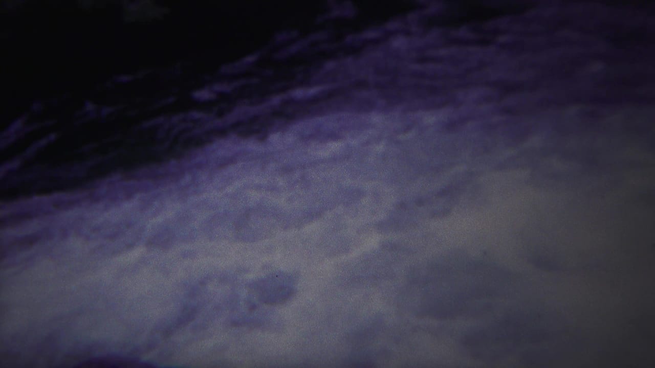 Turbulent water surface with pale foam under dark shadow.
