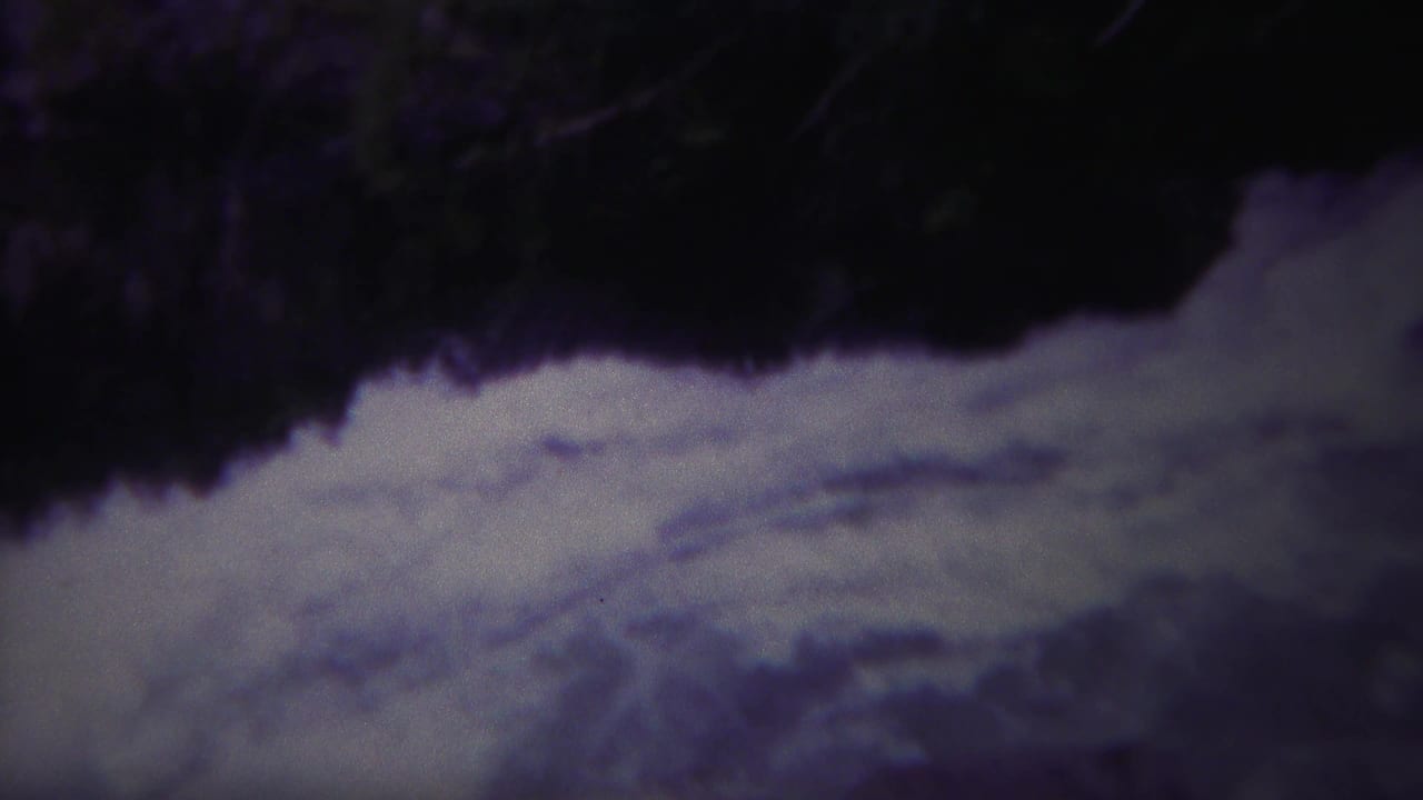 Vintage Yellowstone 8mm view of bright rapids against a dark river edge, with soft focus and color shift.