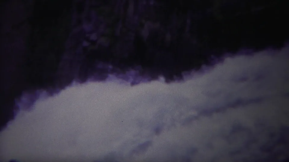 1967 Yellowstone home-movie frame of fast water coursing along a dark rocky river edge.