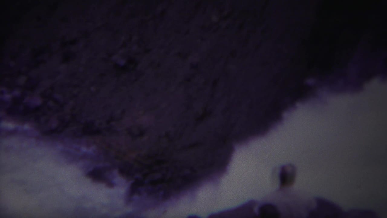 Turbulent pale water passes between dark rocky edges in a tilted 8mm frame.