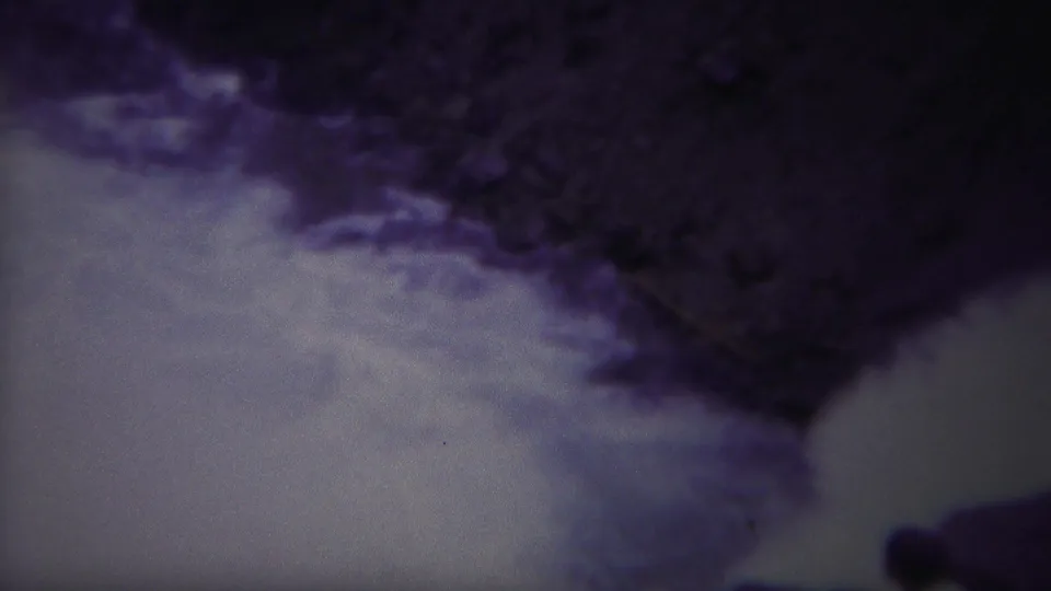 A handheld 1967 Yellowstone river view shows foamy water below dark rock, with a distant person partly visible near the lower frame.