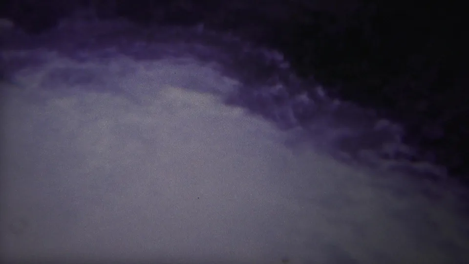 A Yellowstone 8mm frame shows whitewater below a dark rock ledge, with a distant person near the right edge and visible film fading.
