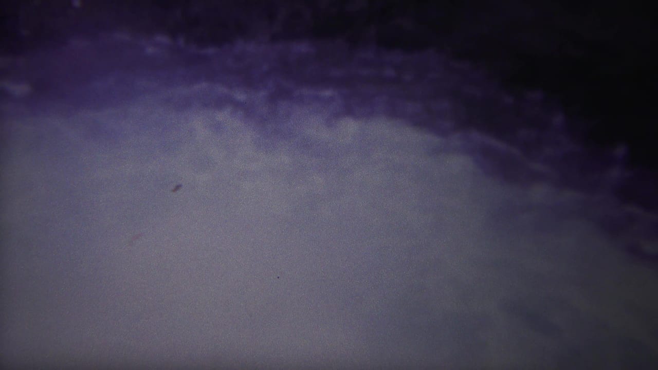 Soft pale water churns below a dark purple band.