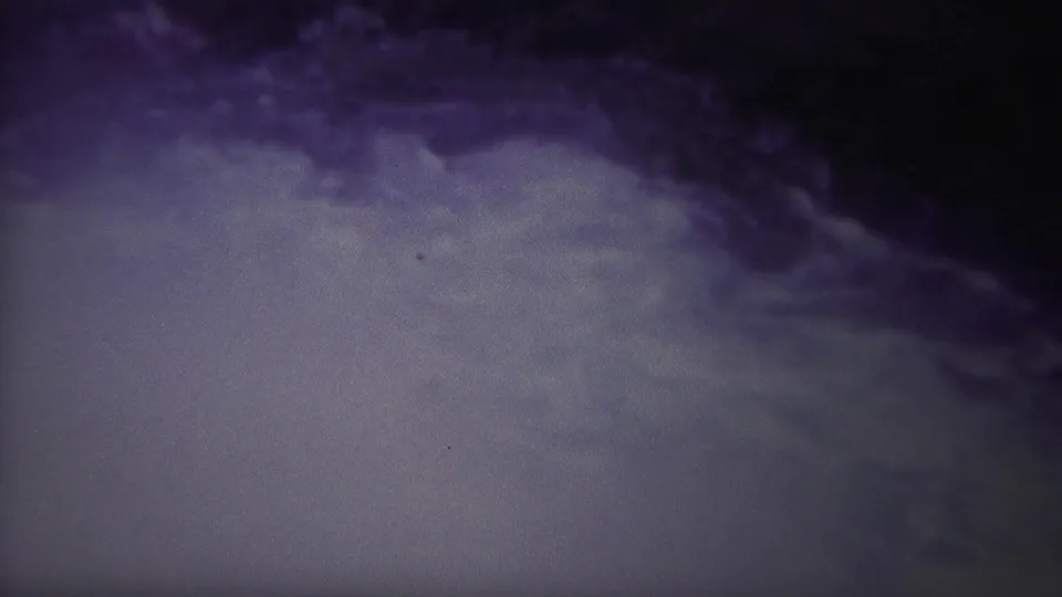 Archival 8mm frame from the Yellowstone, Wyoming clip showing pale turbulent river water beneath a dark shadowed outflow area.