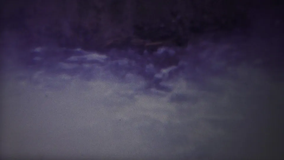 1967 Yellowstone home-movie frame with churning river water, a dark upper bank, and pronounced grain from the 8mm source.