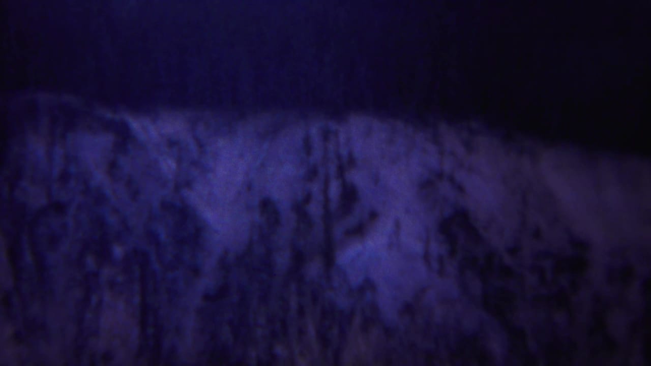 Shadowed rocky or earthen texture under deep blue and violet tones.