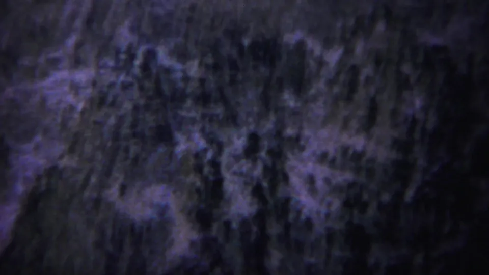 1967 Yellowstone 8mm frame showing a dark, steep canyon wall with rough rock texture and shadowed vegetation.