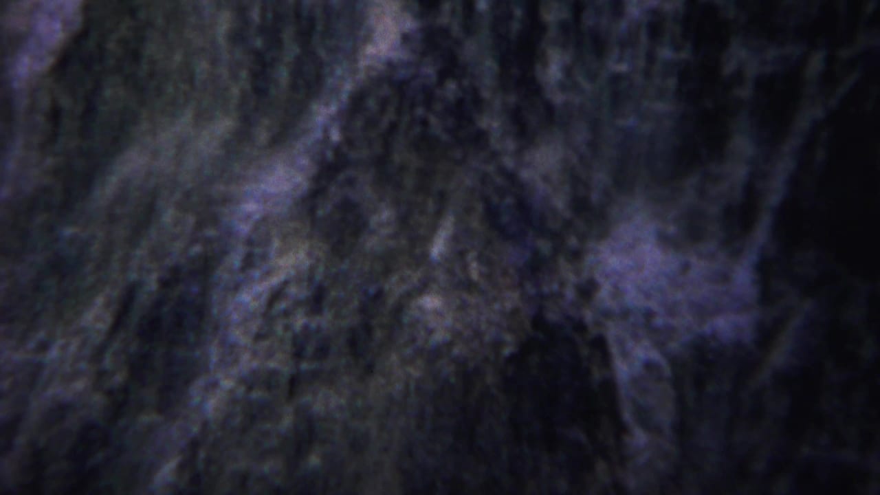 Vertical canyon face with dark trees and blurred rocky texture.