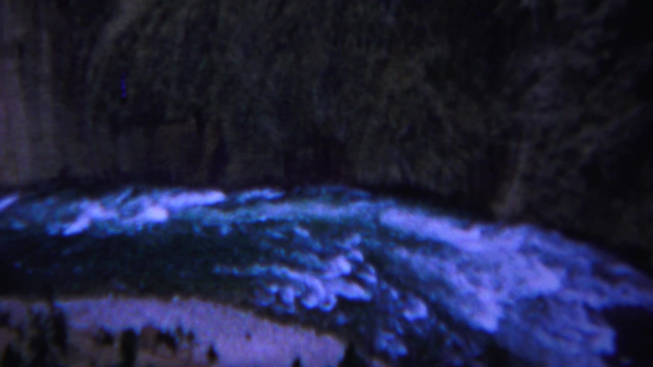 Rushing blue-tinged river water below dark forested canyon edges.
