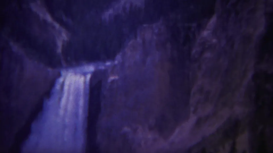Yellowstone waterfall footage from 1967 showing cascading water beside dark cliffs and lower evergreen forest.