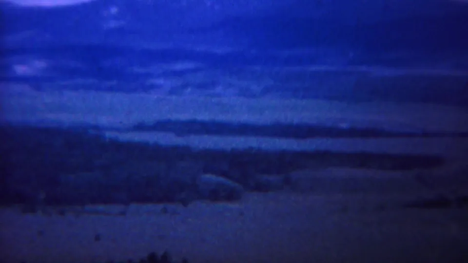 Likely Yellowstone, Wyoming landscape frame with distant ridges, valley floor, and aged blue 8mm film color.