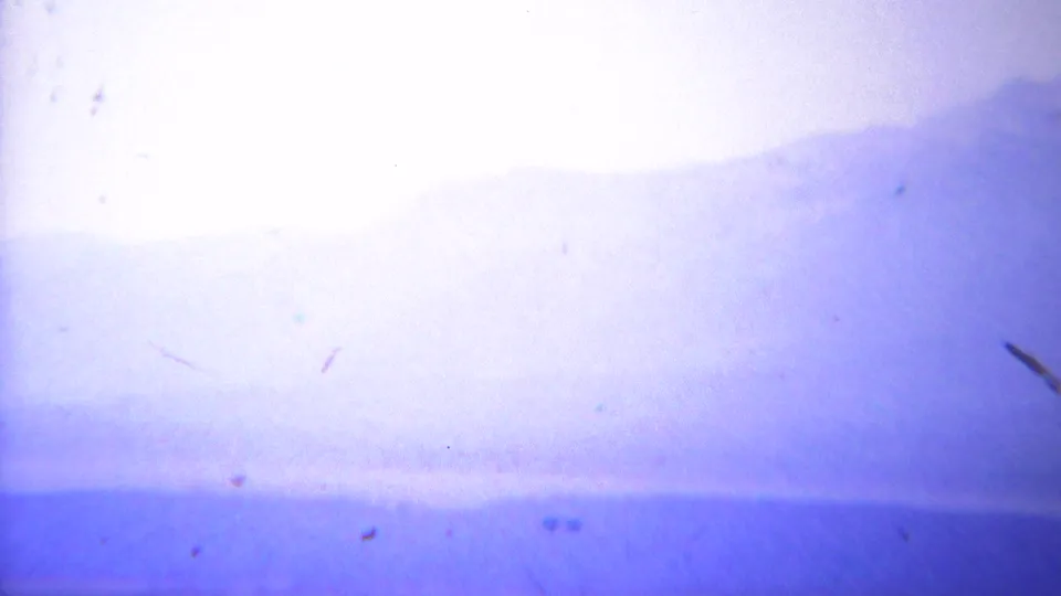 Overexposed 1967 8mm frame of a pale mountain horizon, likely from a Yellowstone travel panorama.