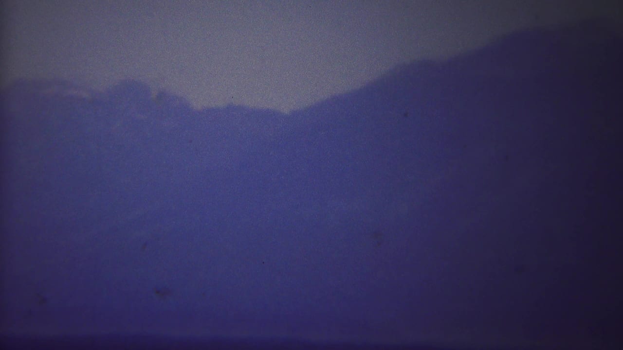 1967 Yellowstone 8mm frame showing a distant mountain ridge softened by mist and purple-blue color drift.