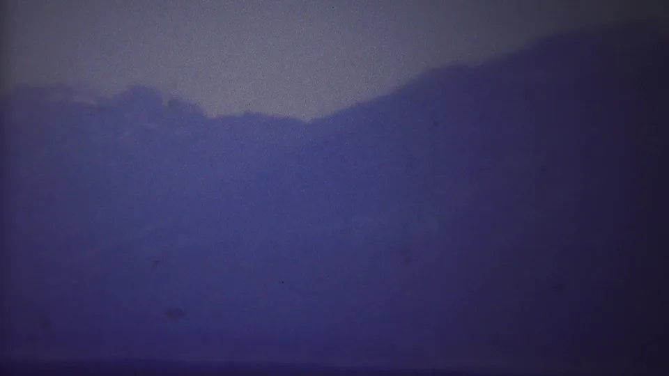 1967 Yellowstone 8mm frame showing a distant mountain ridge softened by mist and purple-blue color drift.