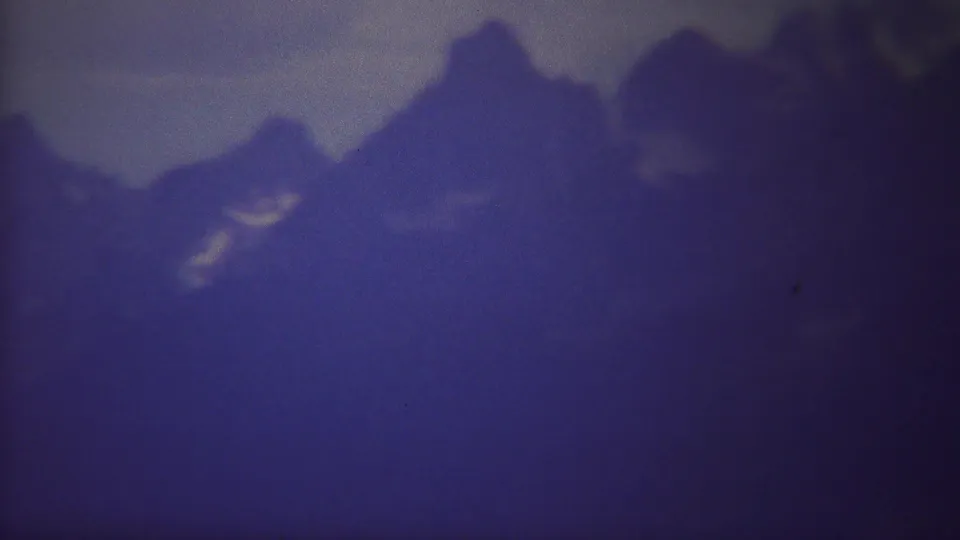 A hazy 1967 Yellowstone 8mm view of mountain peaks, with muted color and light film speckling.