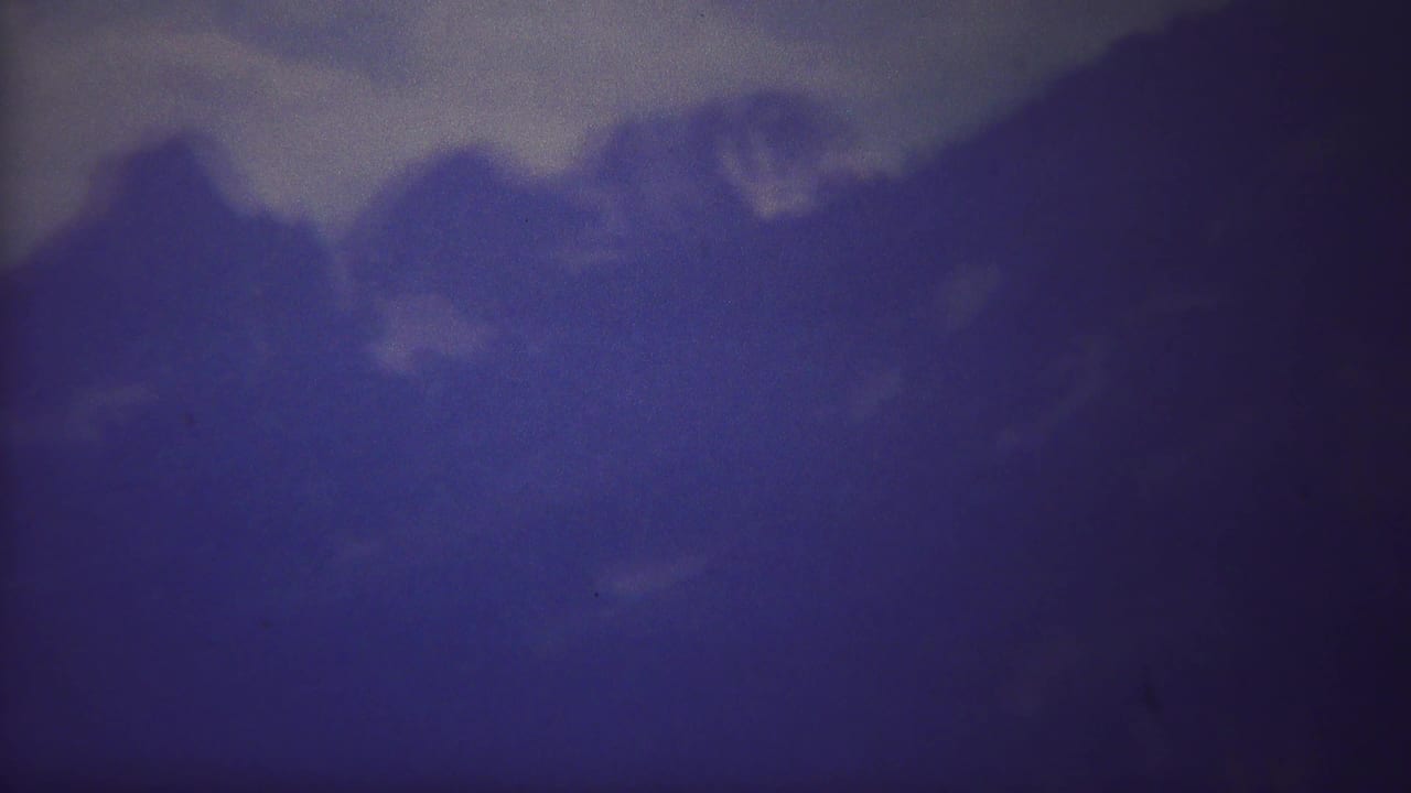 Dark blue mountain peaks beneath a cloudy sky.