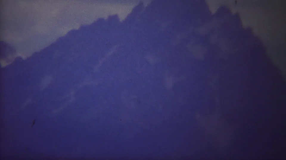 1967 Yellowstone 8mm frame with a broad snow-dusted mountain ridge receding into low cloud and haze.