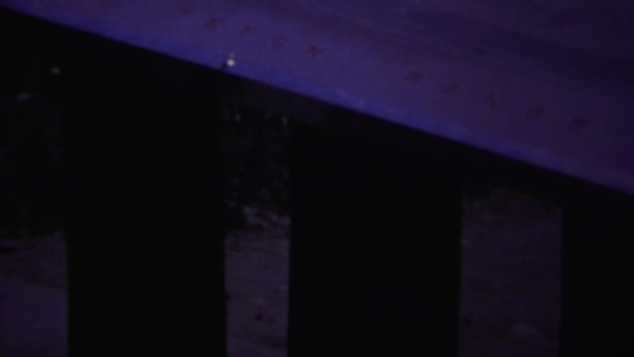1967 Yellowstone 8mm frame showing shadowed vertical slats and a pale wooden surface with heavy purple-blue color shift.