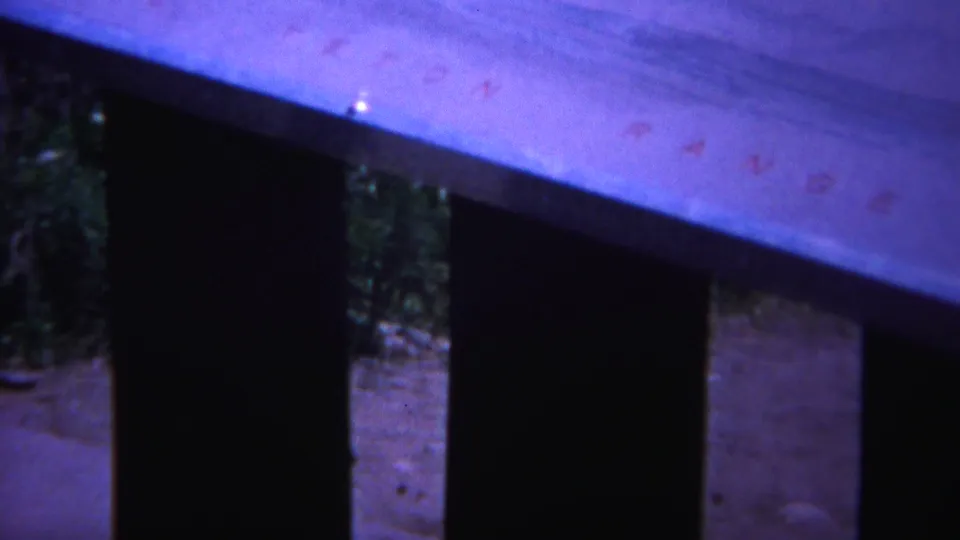 Final 1967 Yellowstone 8mm frame showing dark slats under a pale wooden board with faint reddish marks in the film image.
