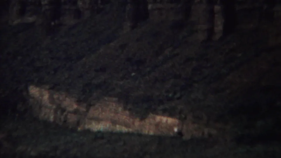 Yellowstone canyon view on 8mm film, with a pale rock shelf beneath a dark, steep hillside.