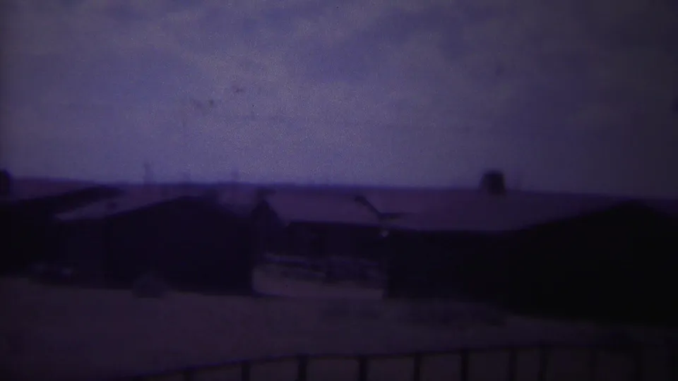 Faded 8mm frame of a small-town building row in Yellowstone, Wyoming, with open ground and a purple color cast.