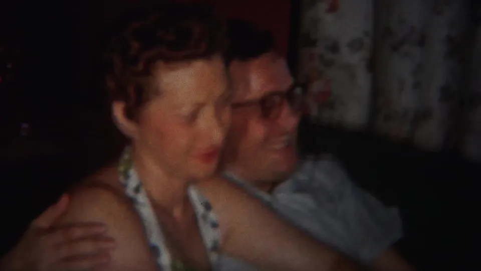 In supported 1951 Westville, New Jersey footage, a woman and a man in glasses sit closely on a couch near floral curtains.