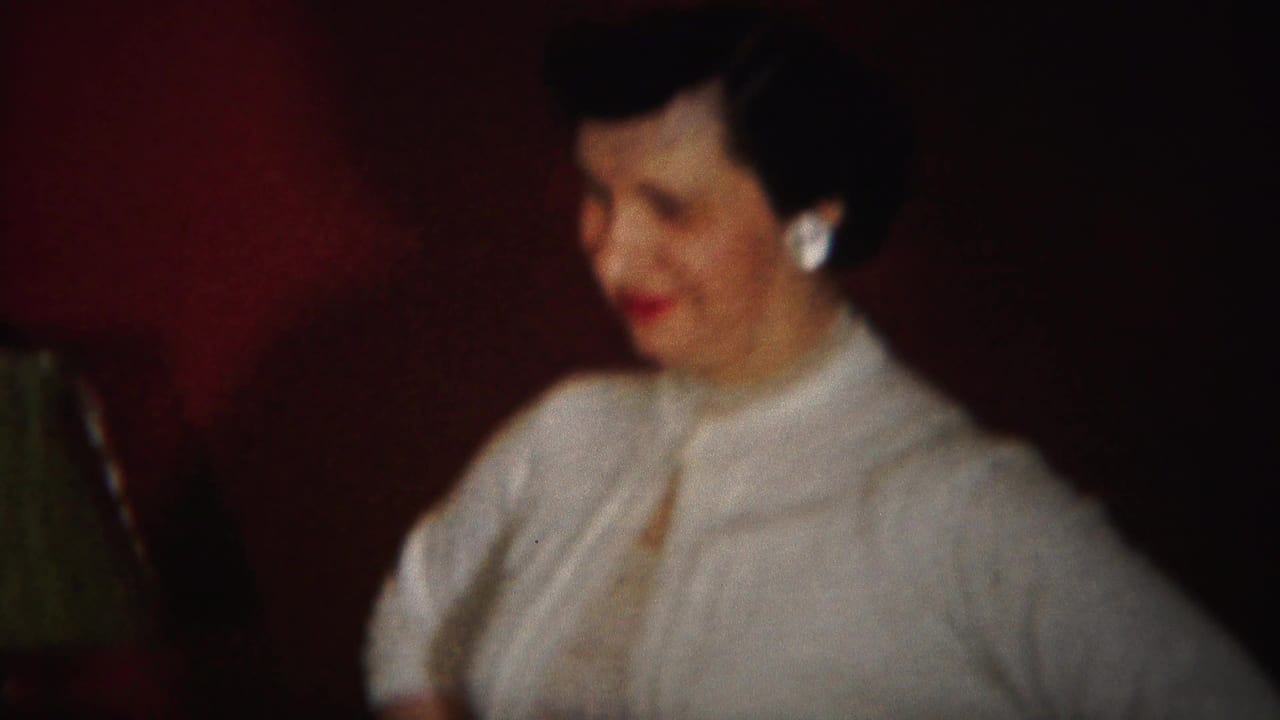 In 1951 Westville, New Jersey home-movie footage, a woman in light clothing and pearl earrings smiles in a dim indoor room.