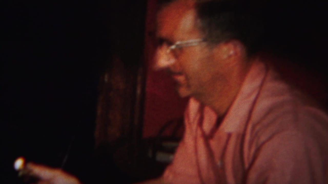 In 1951 Westville home-movie footage, a man in glasses and a pink shirt smiles while seated in a low-lit room.