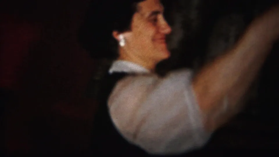 A woman in a white blouse and dark vest appears to dance in a private Westville interior captured on 1951 8mm film.