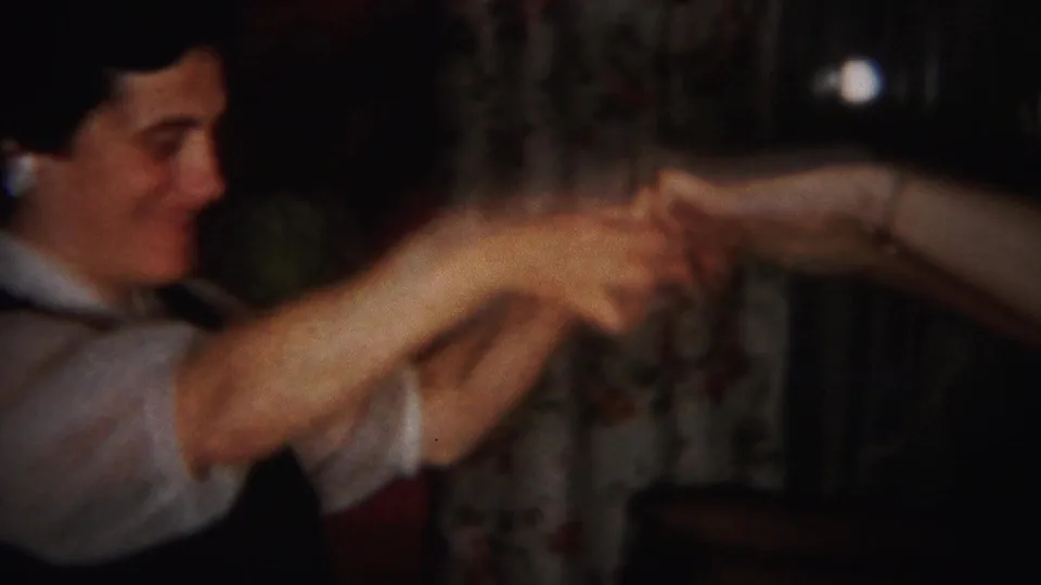 The woman extends both arms while dancing or gesturing toward another person in the 1951 Westville home-movie scene.