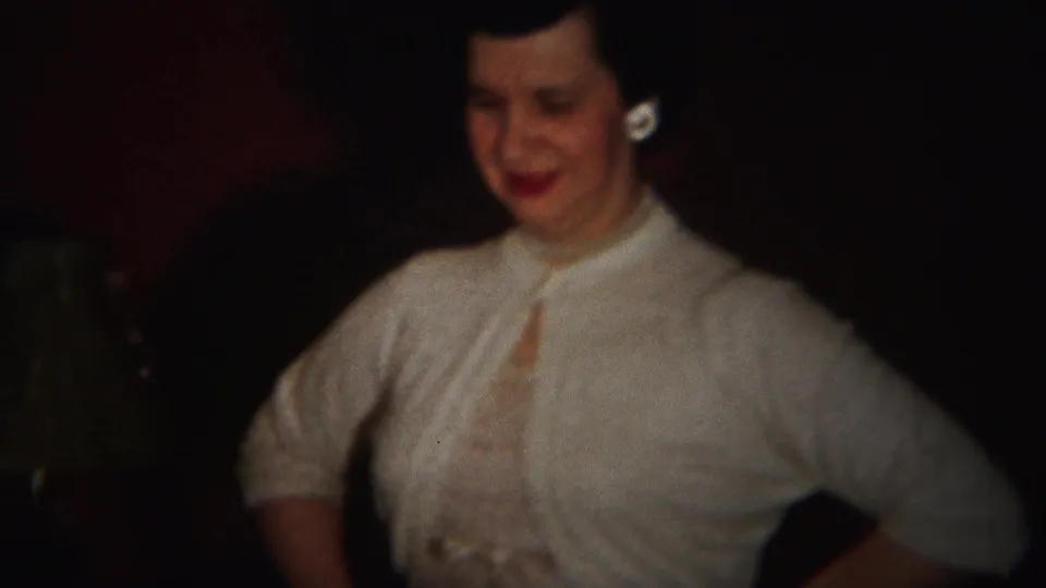 A woman in a light dress or blouse stands with hands at her waist during a 1951 Westville indoor party scene.