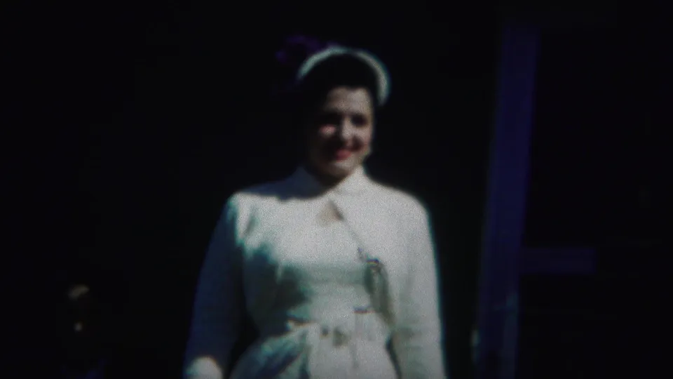 A woman in white formal dress faces the camera as a partially visible person remains in shadow nearby in the 1951 Westville home movie.