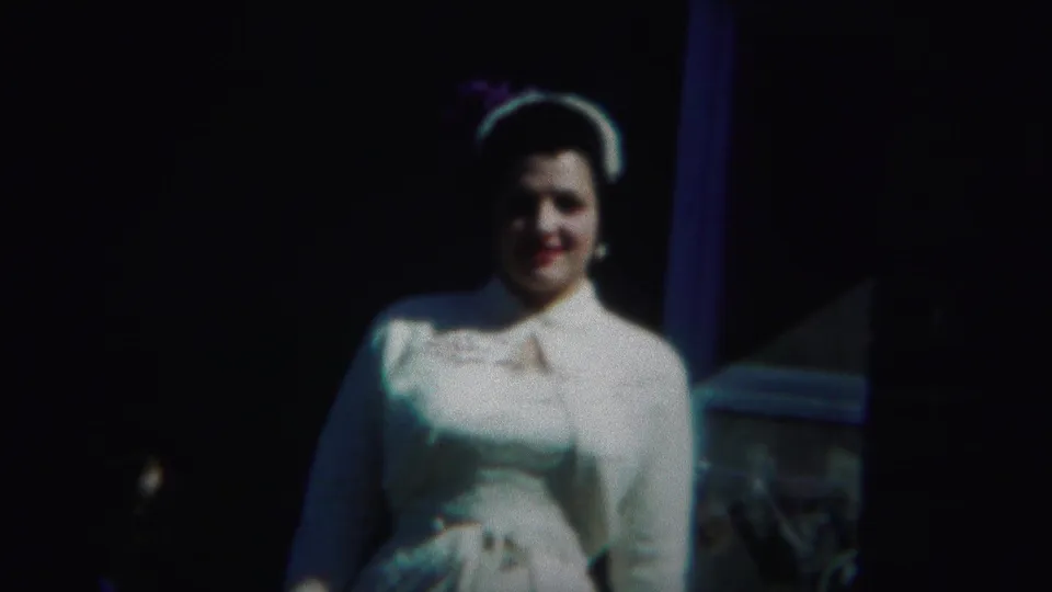 The woman in white stands near a dark structural opening, with bright sunlight and 8mm color shift shaping the 1951 Westville frame.