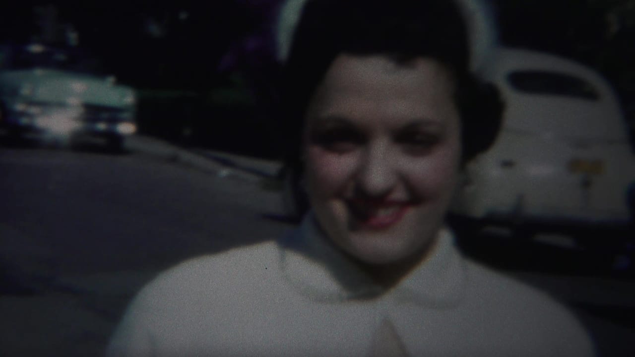 A smiling woman in light clothing stands close to the camera on a Westville, New Jersey suburban street in 1951.