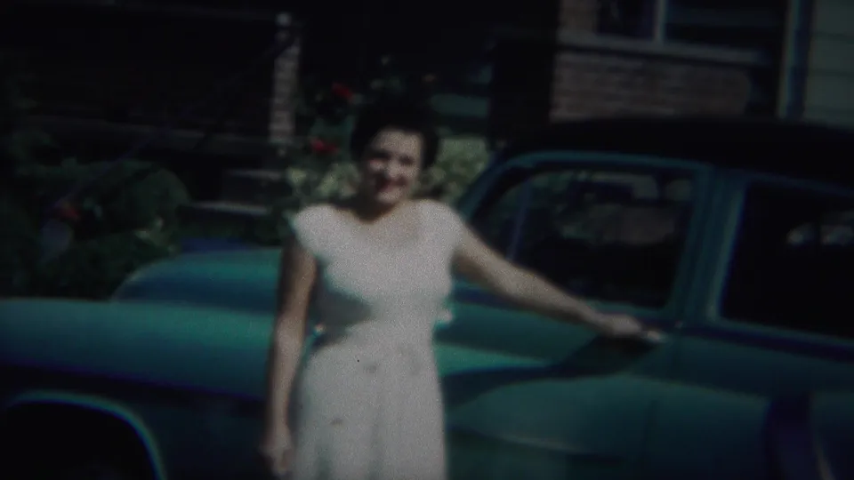 In Westville, New Jersey, 1951, a woman in a white dress poses beside a green vintage car in front of a residence.