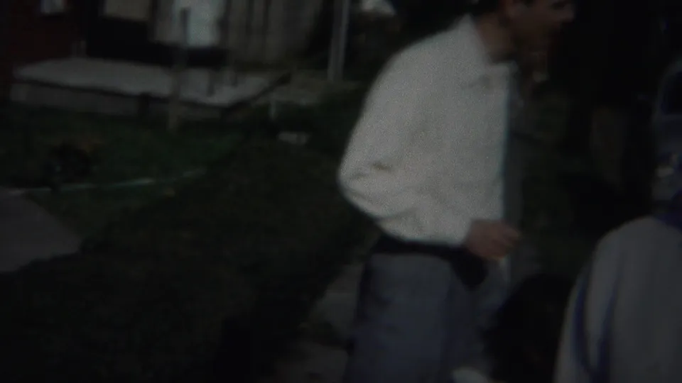 In Westville, New Jersey home-movie footage from 1951, a man in a white dress shirt stands in a dim outdoor residential setting.