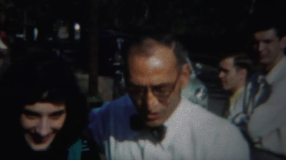 The young woman and older man appear together in the foreground, with several adults and parked cars visible in the 1951 Westville footage.