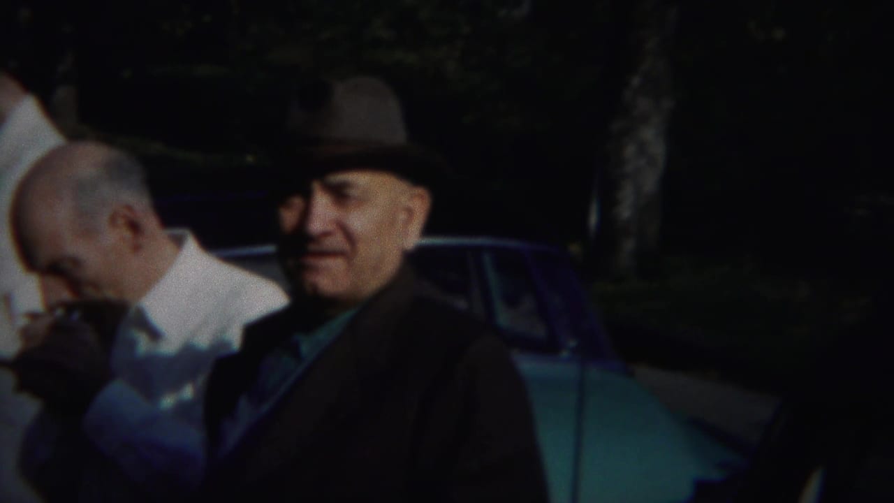 Men in period dress stand outdoors in Westville, New Jersey, with one man smoking and another in a fedora near a blue-green car.