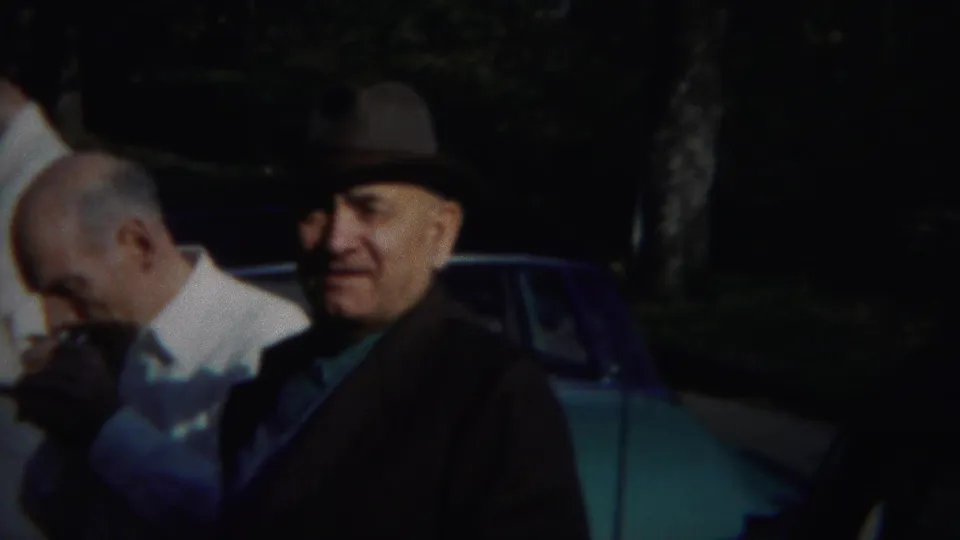 Men in period dress stand outdoors in Westville, New Jersey, with one man smoking and another in a fedora near a blue-green car.